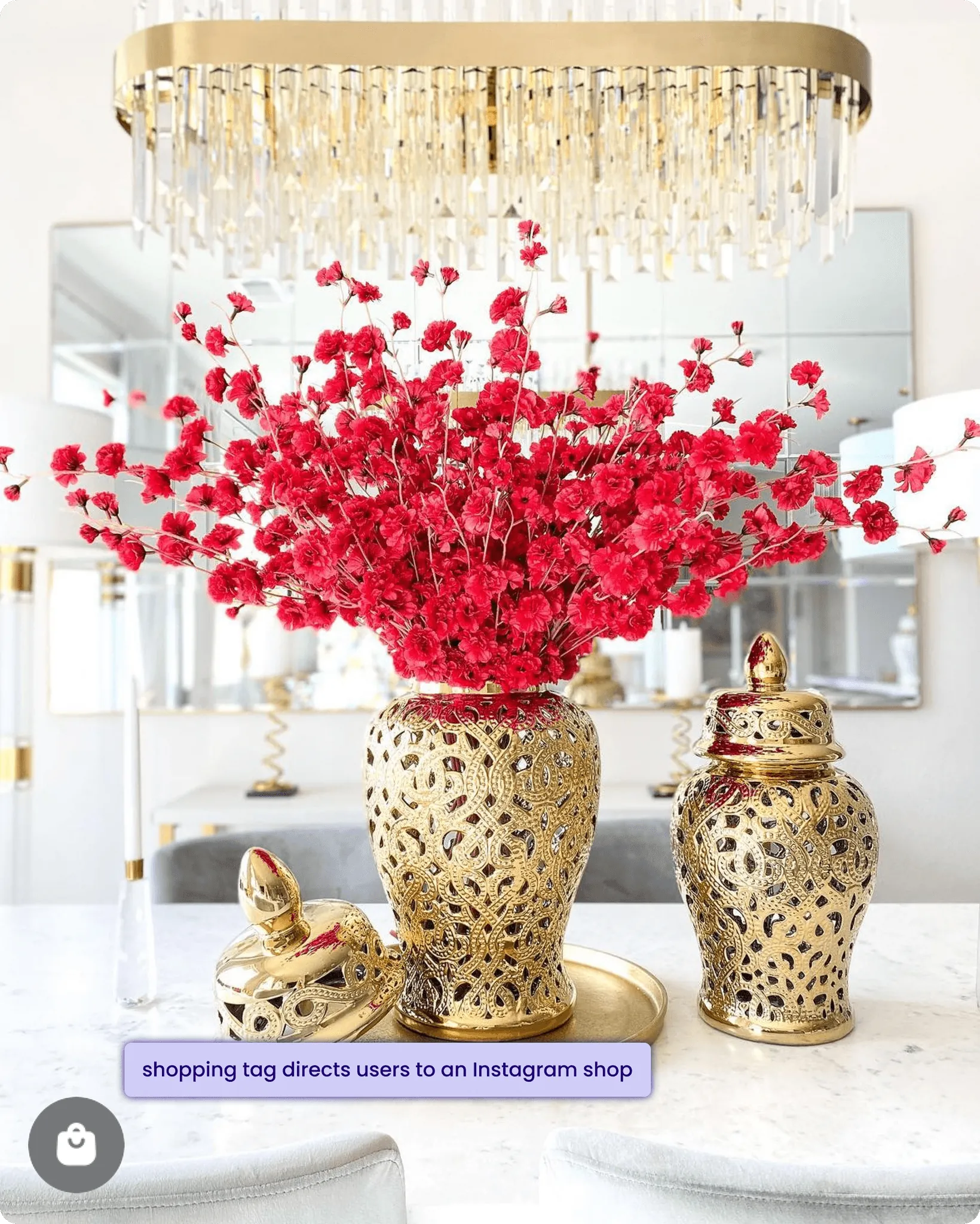 Golden vase with red flowers on a marble table, with a chandelier above